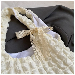 Détail du sac à texture bulles crème avec nœud décoratif en dentelle jaune