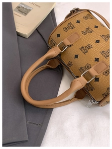 Detailed view of brown lychee leather texture and bear pattern on a boston bag