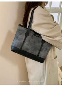 Detail of retro tote bag featuring grey textured fabric and black leather trim accents