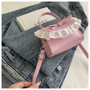 Detail of pink PU leather mini bag featuring white lace trim and a cute bow decoration