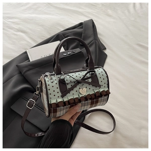 Detail of canvas plaid bag with mint star pattern, brown bow, and metallic heart charm