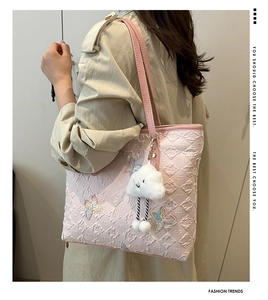 Detail of pink quilted tote bag featuring butterfly embroidery and cloud plush charm