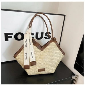 Detail of woven straw tote bag with brown leather trim and decorative ribbon accent