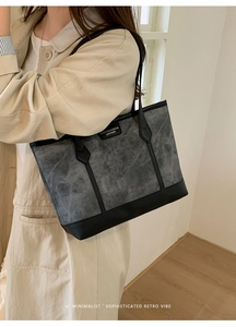 Macro detail of the grey retro tote bag showing faux leather texture and black trim
