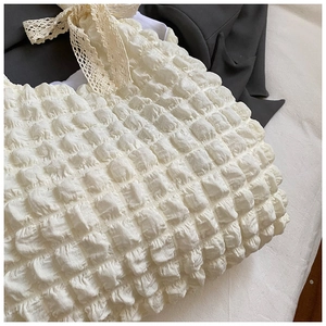 Détail du sac à main popcorn crème montrant la texture 3D et le nœud en dentelle