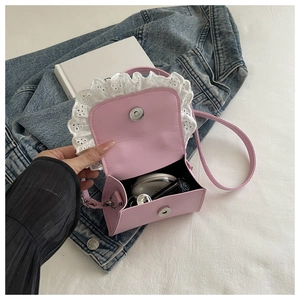 Detail of pink mini crossbody bag showing white lace trim and magnetic snap closure