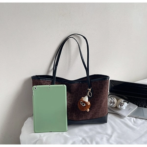 Detailed view of large leopard print tote bag with plush charm and office accessories