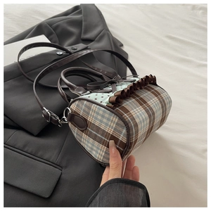 Detail of checkered canvas cylinder bag with bow decoration and leather handle