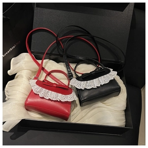 Detail of red and black mini crossbody bags with lace trim and bow in a gift box