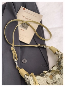 Detail of sequined hobo bag featuring metallic sequins and beige leather strap accents