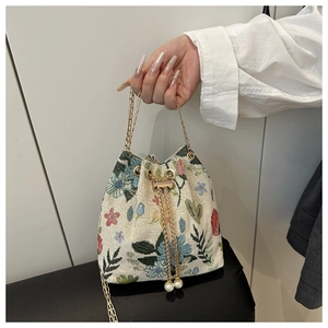 Close-up of retro bucket bag with colorful floral embroidery and pearl drawstring detail