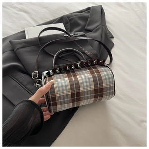 Detail of checkered barrel bag with ruffle trim and brown leather handles on a suit