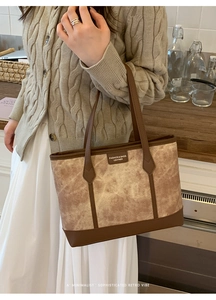 Detail of medium tote bag featuring marble texture fabric and brown leather trim on a model