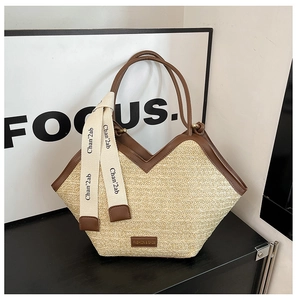 Detail of hand-woven straw tote with brown leather trim and chic fashion logo branding