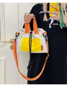 Détail du sac fourre-tout bicolore avec poignées orange et poche avant à bouton jaune