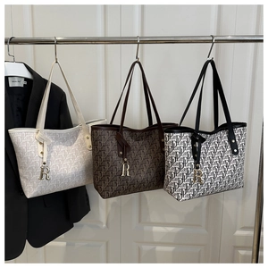 Vue détaillée du motif monogramme et du pendentif R sur les grands sacs fourre-tout