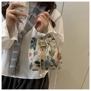 Detail of vintage floral jacquard bucket bag with golden chain strap and pearl charm