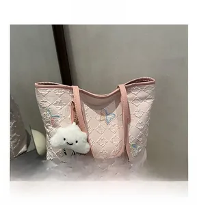 Dettaglio della borsa tote rosa trapuntata con ricamo a farfalla e ciondolo a nuvola