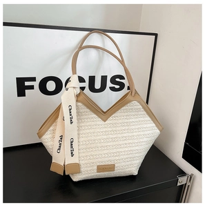 Detail of contrast large tote bag featuring straw texture, webbing strap, and metal logo