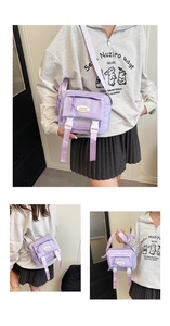 Detail of light purple nylon crossbody bag with fashion label and white buckle closure