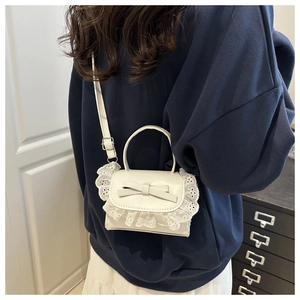 Detailed back view of a white lace mini handbag with elegant bow on a navy sweatshirt