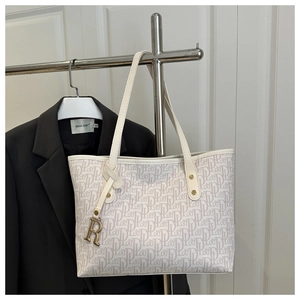 Détail du sac cabas blanc avec imprimé lettres et pendentif R doré sur cintre