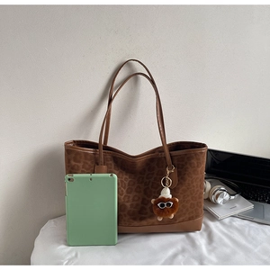 Detail of leopard print tote bag showing large capacity for laptop and plush lion charm