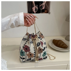 Detailed shot of retro floral jacquard bucket bag with pearl drawstring and gold chain