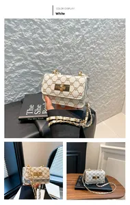 Detail of white mini square bag with brown pattern, metal chain and gold twist lock
