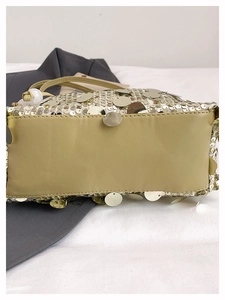 Detail view of the flat leather bottom and shiny champagne gold sequins on the handbag