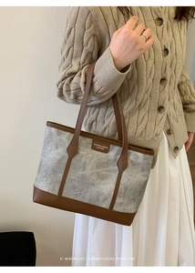 Shoulder shot of large marble pattern tote bag with brown leather handles and brand tag