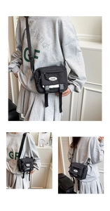 Detail of black nylon crossbody bag featuring buckle straps and adjustable shoulder strap