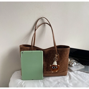 Detailed view of brown leopard embossed tote bag with plush charm and tablet for scale