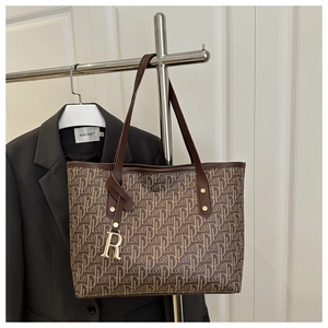 Détail du sac cabas marron vintage avec motif monogramme DL et pendentif R en métal