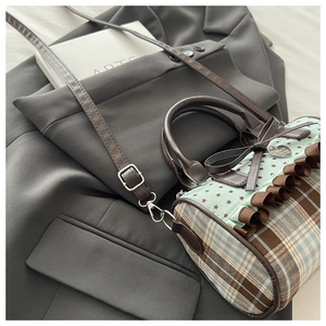 Detail of plaid canvas boston bag featuring ruffles, bow accents and heart charm