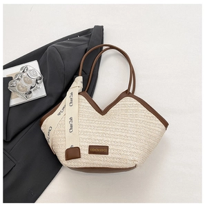 Detailed close-up of straw woven tote with brown leather trim and fashion ribbon detail