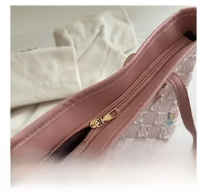 Dettaglio della cerniera dorata e del ricamo a farfalla sulla borsa tote rosa