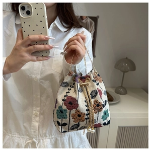 Detail of ethnic floral bucket bag featuring gold chain and pearl drawstring charms