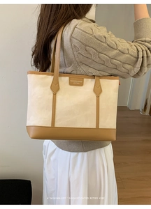 Detail of canvas tote bag with brown leather trim and retro brand plaque for commuters