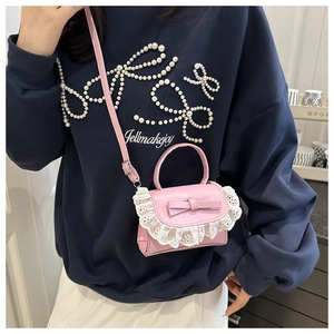 Mini pink crossbody bag with cute bow and lace trim detail worn by model indoors