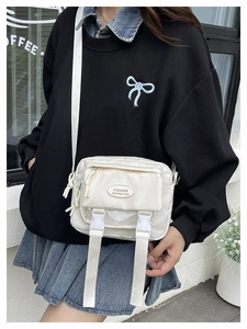 Close-up of white nylon messenger bag with buckle closure and mesh pocket detail