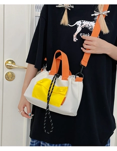 Détail d'un sac fourre-tout tendance avec anses oranges et poche jaune porté par un mannequin