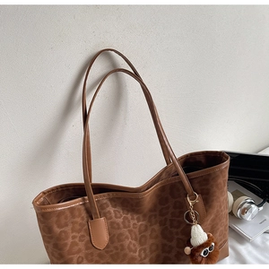 Detail of leopard print tote bag with plush charm and long shoulder straps for daily use