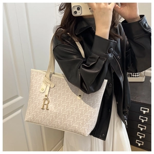 Close-up of vintage monogram pattern and gold metal letter R pendant on the cream tote bag