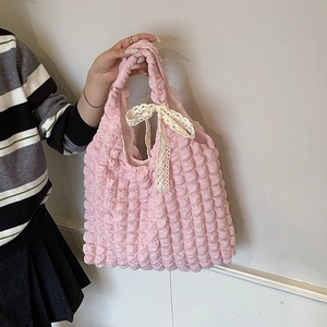 Sac fourre-tout rose à texture gaufrée avec nœud en dentelle porté à la main avec style