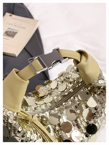 Macro shot of gold sequins and cream leather strap on a stylish underarm bag
