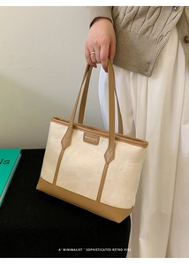 Close-up of vintage canvas tote bag featuring brown leather trim and handle detail
