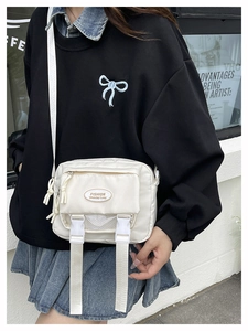 Detail of white nylon messenger bag featuring mesh pocket and fashion logo on front