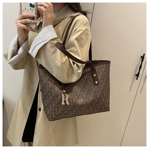 Vue portée d'un grand sac cabas monogramme marron et beige avec breloque dorée R