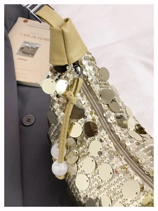 Detailed close-up of golden sequins and marble beads on a leather handle shoulder bag